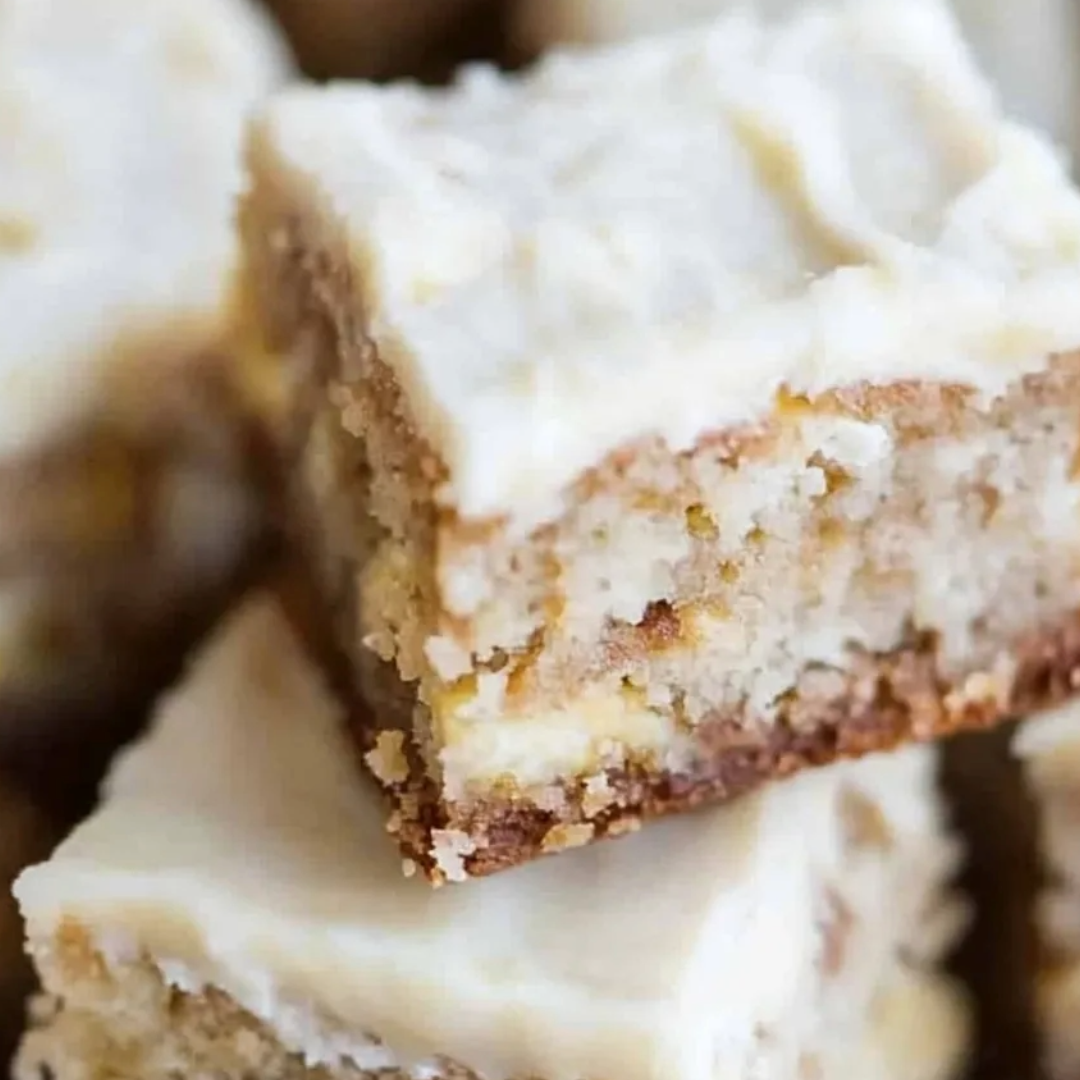 A square piece of cake with white frosting and brown crust.