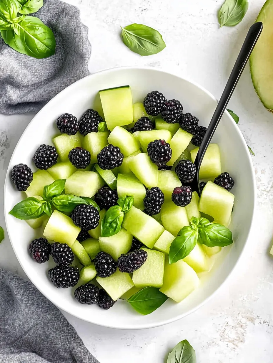 Un bol de salade de melon, mûres et basilic.