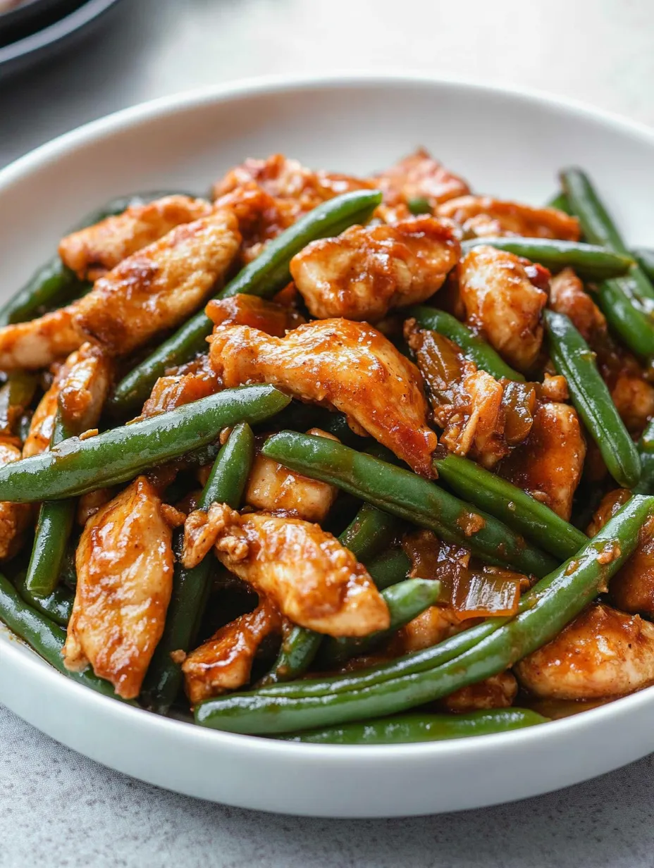 Une assiette de poulet avec des haricots verts.