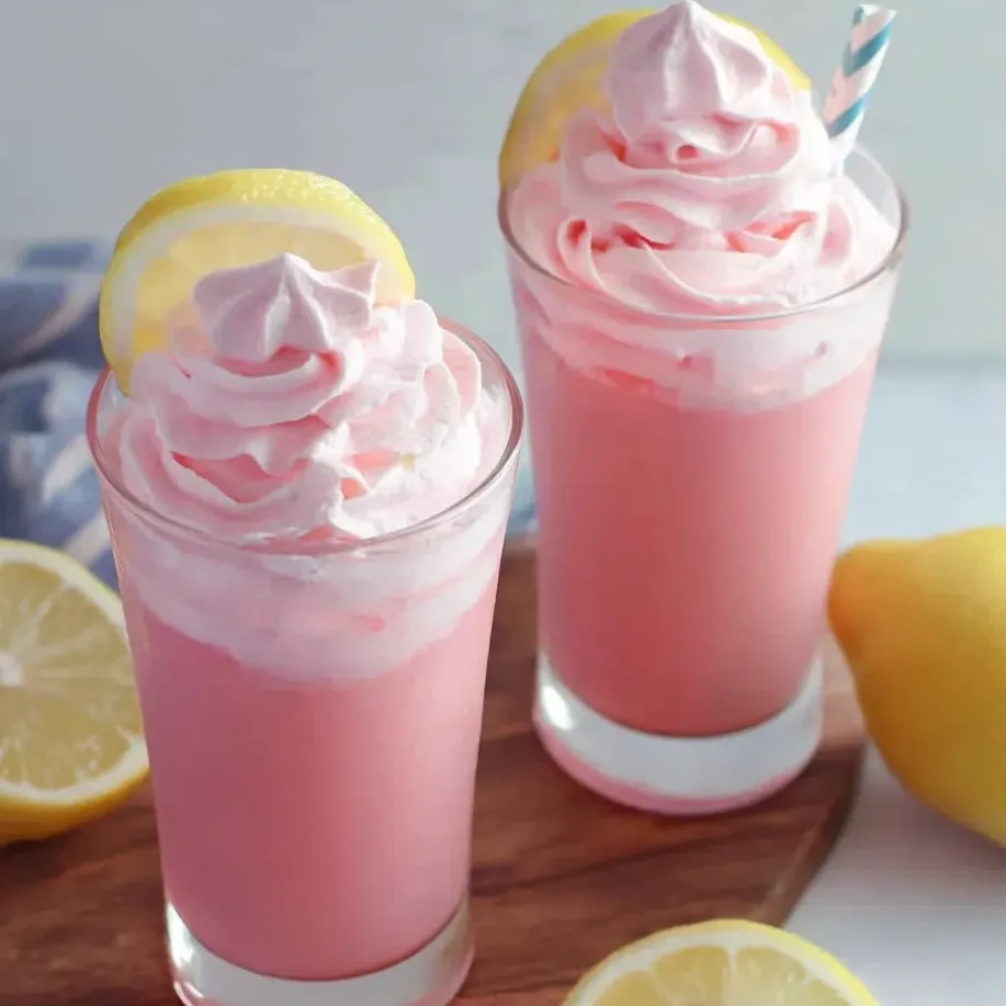 Deux verres de limonade rose avec des rondelles de citron sur une table.