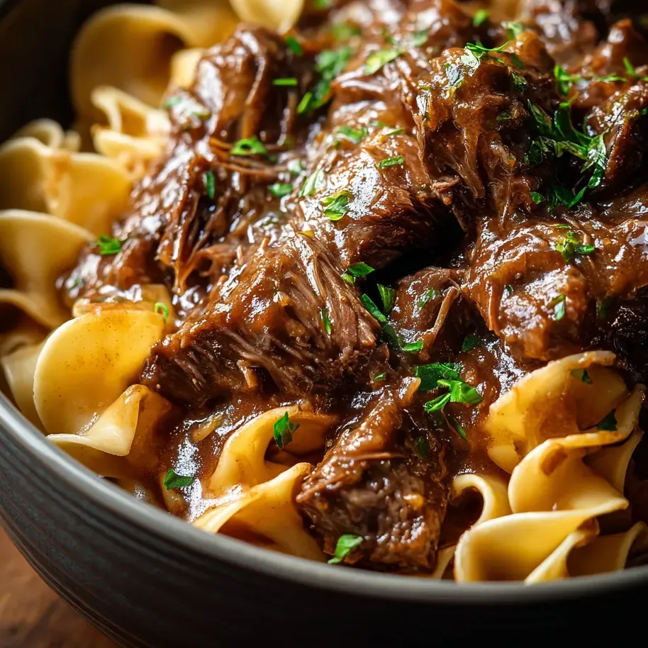 Un bol de pâtes avec du boeuf et de la sauce.