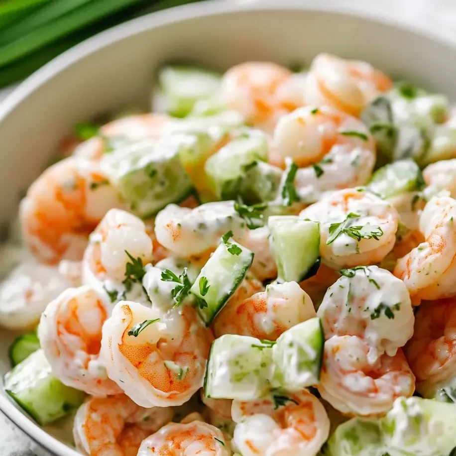 Un bol rempli de salade de crevettes, concombres et d'autres légumes.