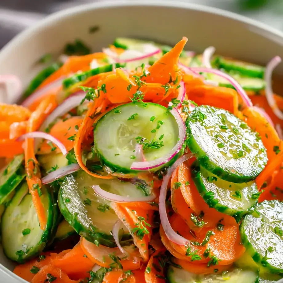 Un bol garni de légumes, avec carottes, concombres et oignons.
