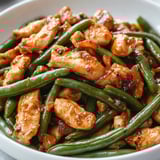 Une assiette de poulet avec des haricots verts.