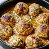 Un bol de boulettes dans une sauce brune.