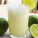 Un verre de citronnade brésilienne avec des limes à côté.