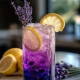 Un verre violet avec tranches de citron et lavande.
