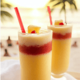 Deux verres de jus d’ananas avec des pailles rouges.