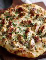 Une pizza garnie de poulet et fromage.