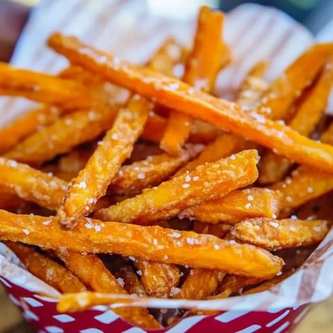 Un panier de frites sur fond de papier à motif vichy rouge et blanc.