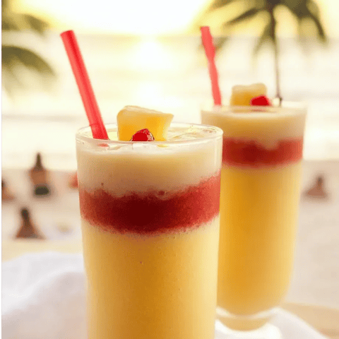 Deux verres de jus d’ananas avec des pailles rouges.
