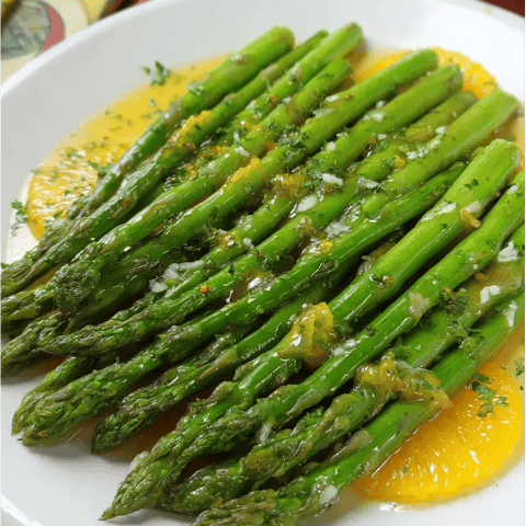 Une assiette d’asperges nappées de sauce.