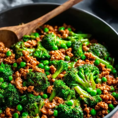 Petit plat noir garni d'une poêlée de dinde, brocoli, petits pois et tomates.